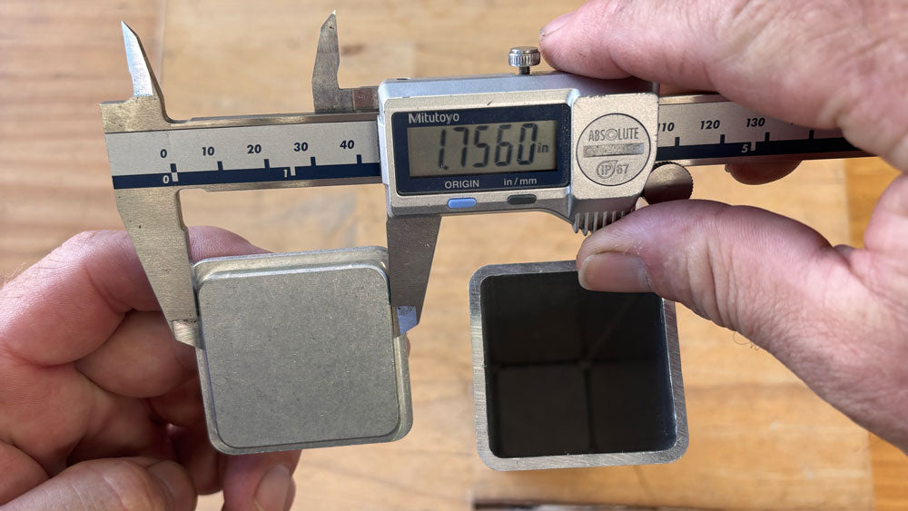 Digital calipers measuring the underside of a square aluminum end cap for precise interference sizing