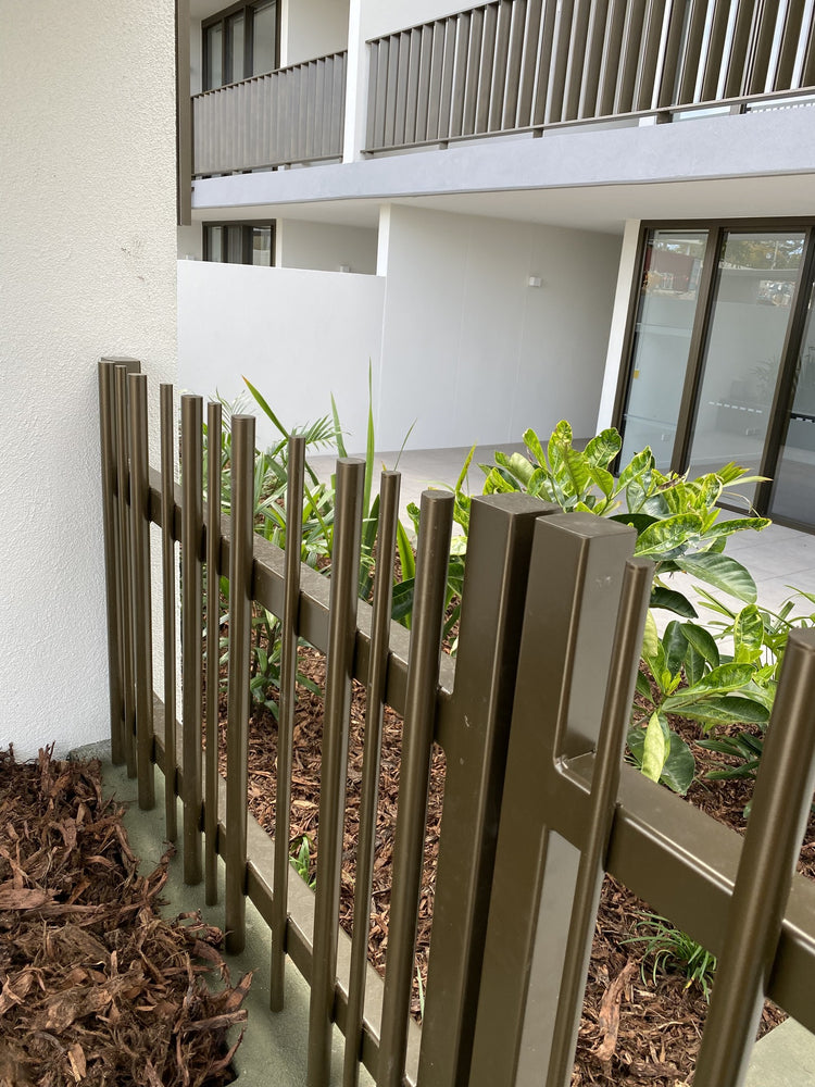 Circular and rectangle aluminum fence with a garden behind it