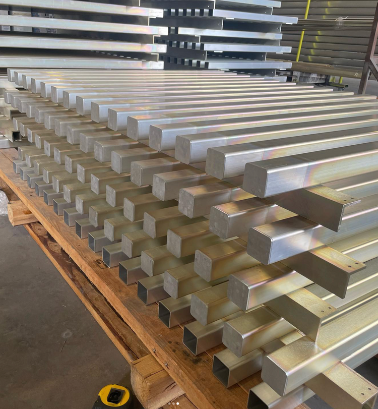 Stacks of aluminum rectangular bars on a wooden pallet in an industrial setting