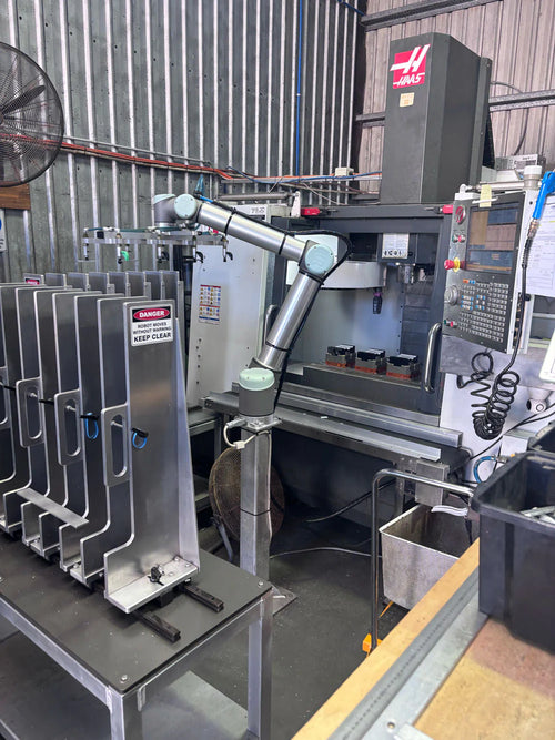 Robotic arm beside CNC machining center in aluminum end cap factory