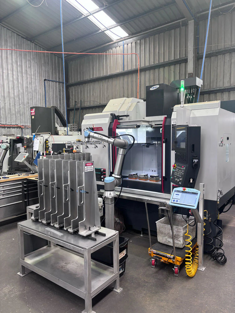 Industrial machine shop with CNC machines and a robotic arm and aluminum end caps in a warehouse setting