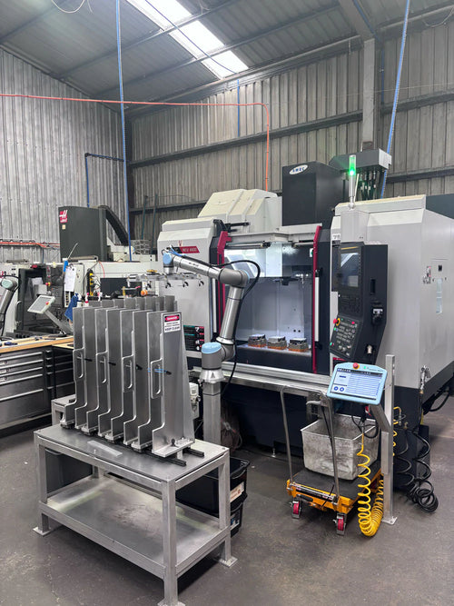 Industrial machine shop with CNC machines and a robotic arm and aluminum end caps in a warehouse setting