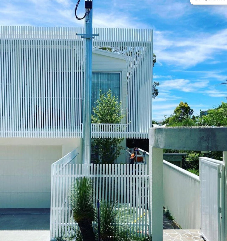 White aluminum architectural screening with vertical battens capped using precision aluminum end caps.