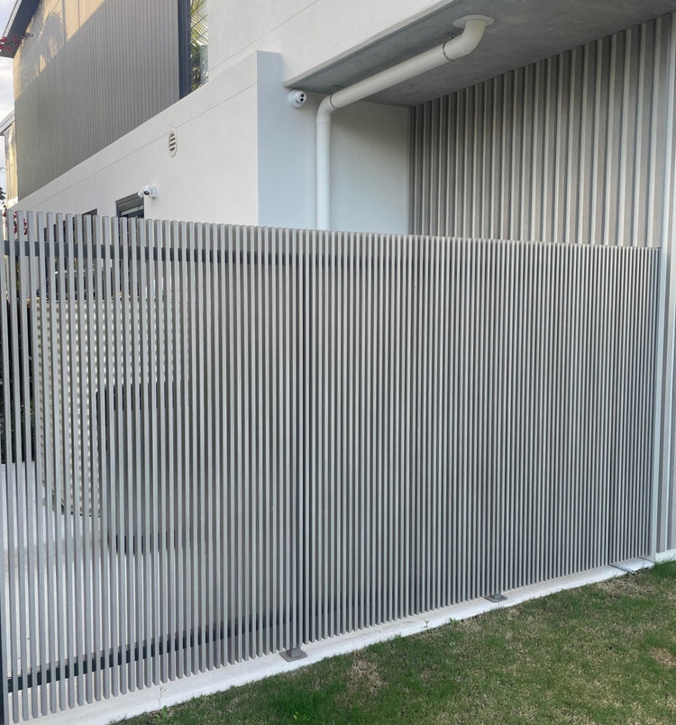 Grey vertical aluminum privacy screen with slim battens finished using interference-fit aluminum end caps.